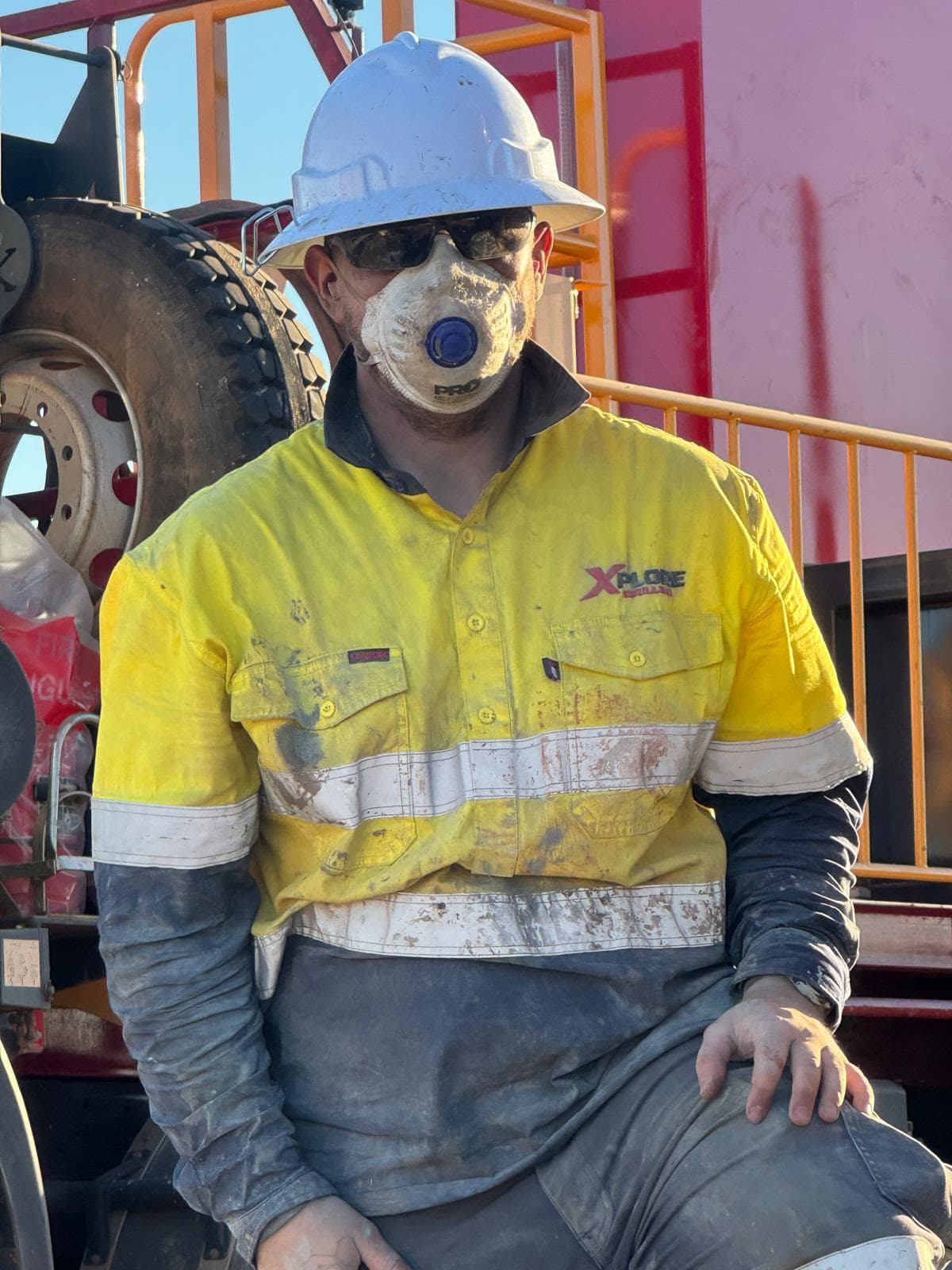 Xplore Drilling crew member in full PPE — hard hat, safety glasses and dust mask