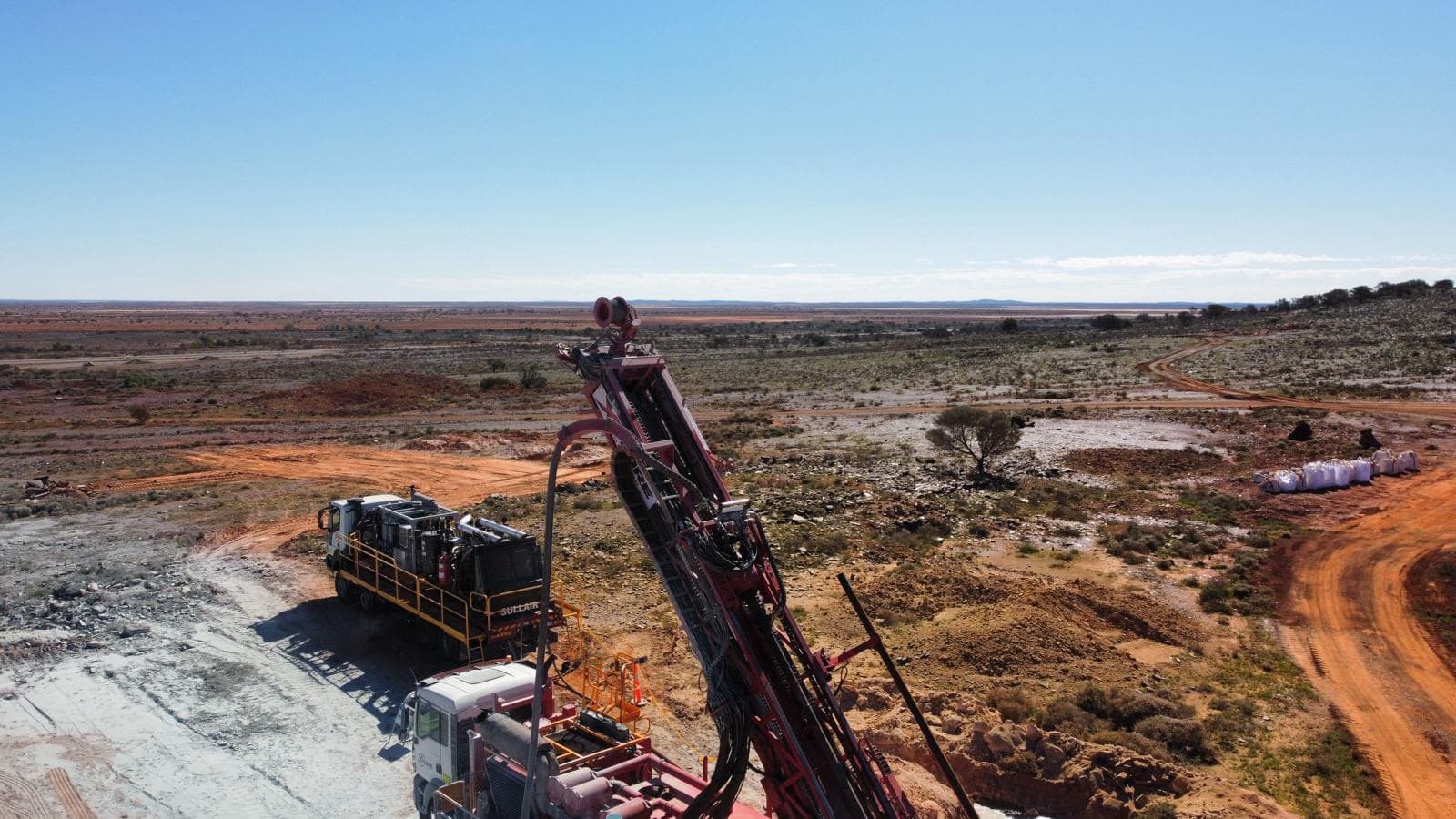 Drill rig mast rising over a remote Western Australian outback panorama